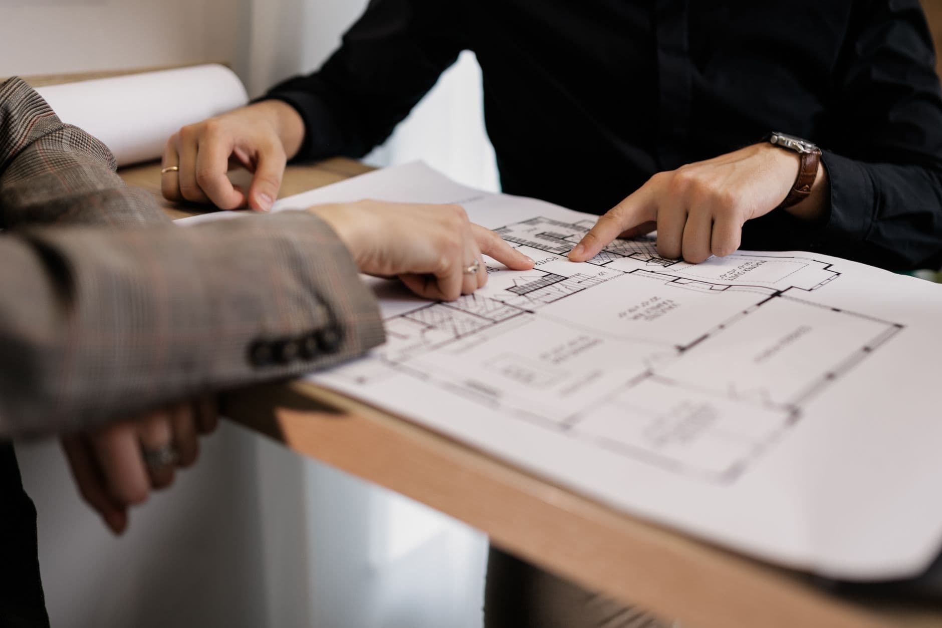 Zwei Fachleute besprechen gemeinsam einen Gebäudeplan am Arbeitstisch